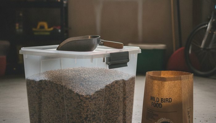 Sealed plastic bird seed storage container sitting in a garage